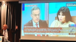 Raed Arafat se suie cu picioarele pe Antena 3 și România TV la o conferință în Bruxelles: